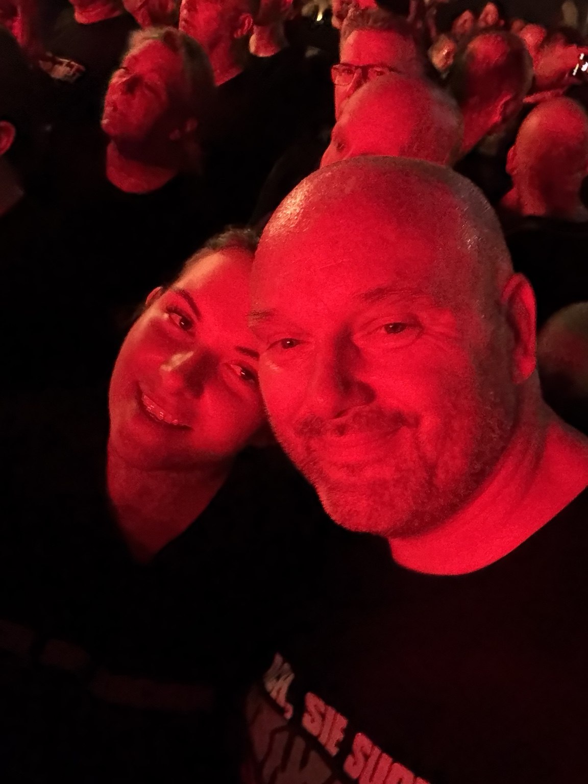 Stefan und seine Partnerin während eines Konzerts im roten Bühnenlicht